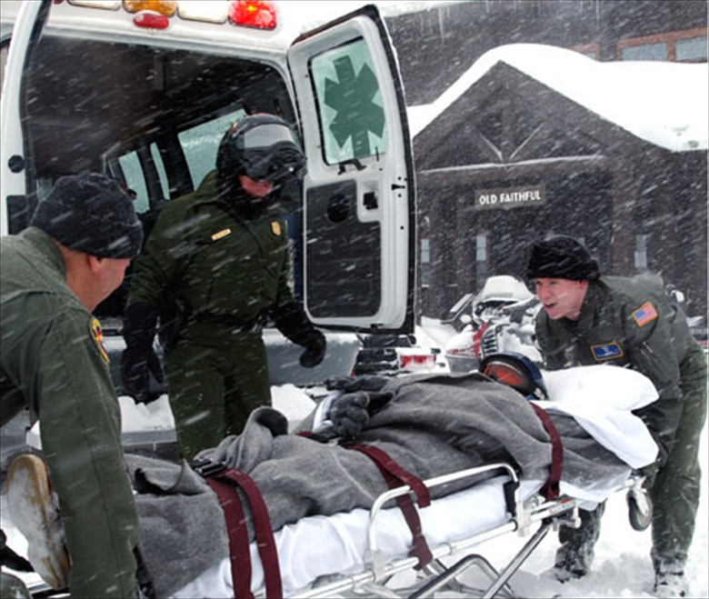 EMTs transporting a patient on a stretcher to an ambulance in the snow